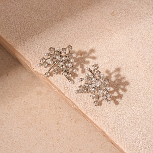 Elegant floral silver earrings with zirconia and pearls on natural stone background