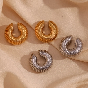 Detail of twisted hollow hoop earrings in gold and silver finish on silk fabric