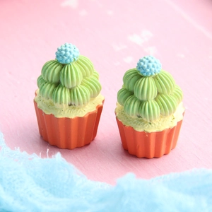 Macro view of two colorful miniature resin cupcakes with green frosting and blue topping