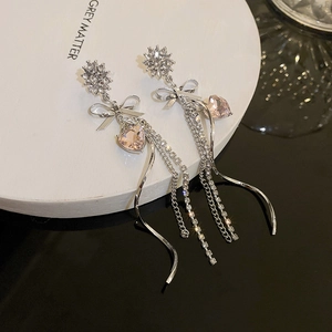 Detail of silver drop earrings with crystal bow, pink heart stone and long tassels