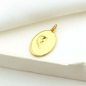 Macro detail of a golden oval pendant with stylized embossed patterns on textured background
