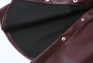 Makro-Detail der weinroten PU-Ledertextur mit Metalldruckknöpfen und schwarzem Futter