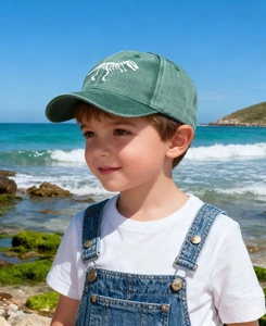 Close-up of white dinosaur skeleton embroidery on a vintage green kids baseball cap