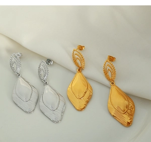 Macro shot of rhombus gold and silver drop earrings with textured leaf pendants