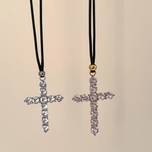 Macro shot of 18k gold and silver cross pendants with zircon on black braided cords