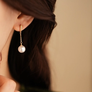 Close-up of gold plated pearl drop earring with zircon on model for a vintage French look