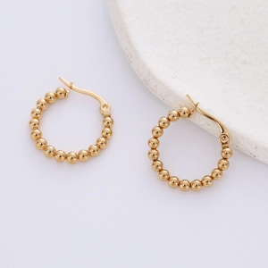 Elegant gold beaded hoop earrings in minimalist style shown on a natural stone base