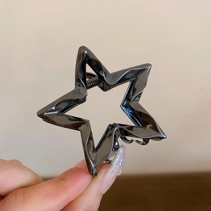 Detail of star-shaped gunmetal hair claw clip with a polished metallic mirror finish