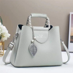 Detailed macro of mint green lychee grain leather handbag with metal leaf pendant
