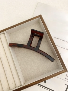 Detailed view of large tortoiseshell claw clip with rectangle hollow design on wood tray