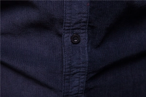 Detailed macro view of navy corduroy fabric texture and premium round button on shirt