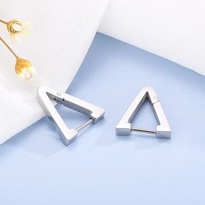 Macro detail of silver geometric triangle stud earrings on white linen with dried flower