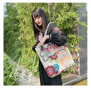 Detailed embroidery of cartoon owl and floral patterns on canvas tote bag with rope handles