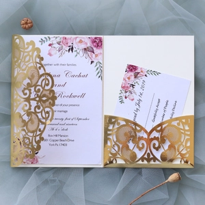 Detailed view of laser-cut gold wedding invitation with pink floral inner cards and envelopes