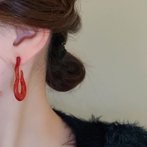 Close-up of bright red wavy flame earrings worn by model for a stylish look