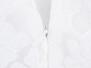 Detail view of a white invisible zipper on delicate lace and embroidered fabric texture