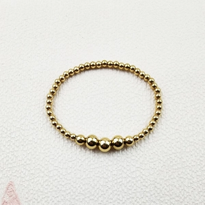 Detail view of handmade gold beaded bracelet with polished stainless steel beads on fabric