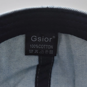 Detailed macro view of internal 100% cotton label and stitching on light blue denim hat