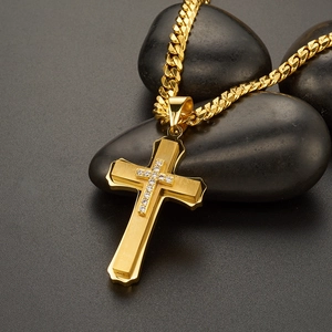Detail of gold cross pendant with zircon stones on a classic cuban chain on black stones
