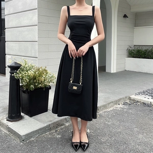 Detail of waist-pleated black A-line midi dress with square neck and elegant silhouette