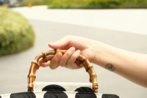 Close-up of a vintage polka dot bag with natural bamboo handle in a stylish outdoor setting