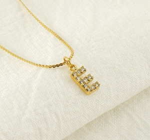 Close-up of gold plated letter E pendant with crystals on a delicate box chain