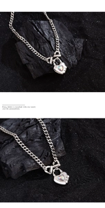 Detail of heart lock necklace featuring a rainbow crystal and thick silver Cuban chain