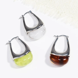 Dettaglio degli orecchini in resina a forma di U nei colori bianco, verde e ambra