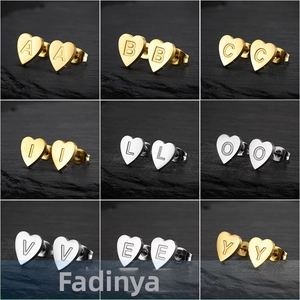 Macro view of heart-shaped stainless steel earrings with engraved alphabets in gold and silver