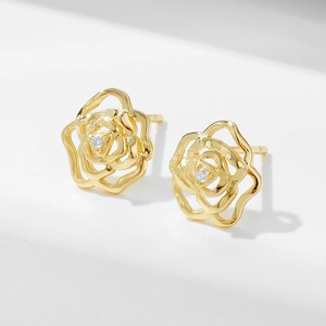 Detail of gold rose stud earrings with a clear center zircon on a minimalist white base
