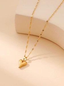 Detail of a golden heart pendant necklace on a minimalist geometric stone display