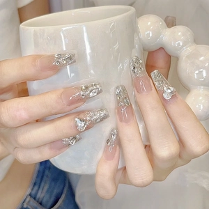 Close-up of nude gradient press-on nails with silver glitter and rhinestone accents