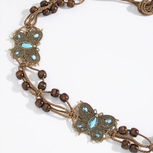 Close-up of bohemian braided belt with wooden beads and bronze butterfly buckle