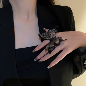 Detail of black acrylic butterfly ring with rhinestones worn on a model's hand