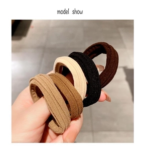 Close-up of four thick high-elastic knitted hair ties in brown, black, and beige colors