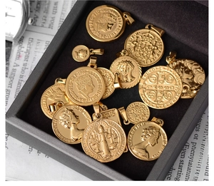 Macro shot of gold Roman coin pendants featuring Queen Elizabeth and Saint Benedict icons