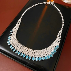 Detail of silver tassel necklace featuring blue teardrop stones and clear crystals