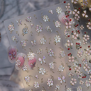 Detail of pearlescent floral nail stickers with golden edges and butterfly patterns