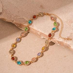 Macro detail of gold necklace featuring teardrop colorful crystals and halo pavé settings