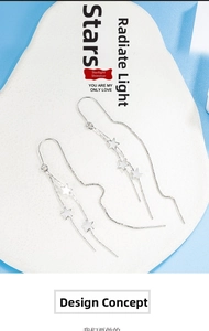 Detailed view of silver star tassel earrings with long chains on a white display board