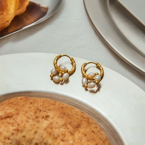 Elegant gold stainless steel hoop earrings with white pearls on a silver plate