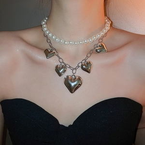 Close-up of layered necklace with white pearls and five silver heart-shaped charms