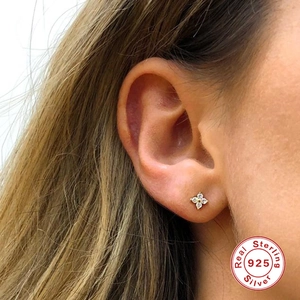 Detail of 925 sterling silver gold-plated flower stud earrings on model's ear