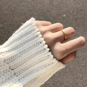 Detailed close-up of a matte finish solid gold band ring worn with a white sweater