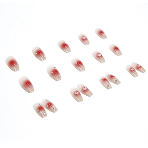 Press-on nail set featuring pink blush gradient with heart patterns and rhinestones