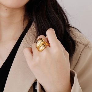 Close-up of a gold sculptural ring with liquid metal design worn by a female model