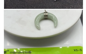 Macro shot of green crescent moon stone pendant with intricate silver wire wrapping detail
