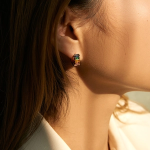 Bohemian 18K gold huggie earrings with rainbow baguette zircons worn by a model