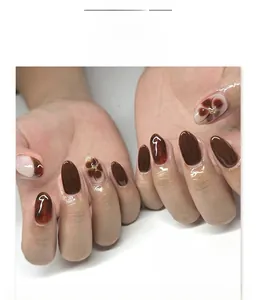 Macro shot of dark red and amber marbled almond nails with floral and gold accents