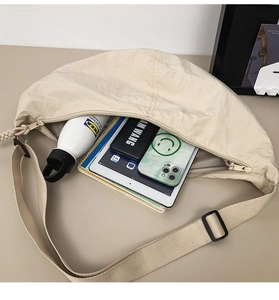 Intérieur spacieux du sac bandoulière en nylon beige montrant le rangement de la tablette